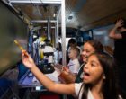 Students aboard the BioBus find microorganisms under the microscope.