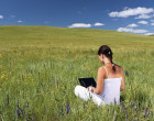 Young woman with laptop on grass