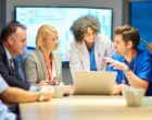 a mixed group of healthcare professional and business people meet around a conference table
