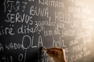 "Hello" written in several languages on a blackboard