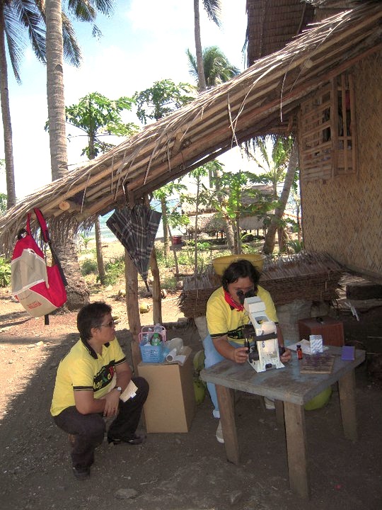 A microscopist in Palawan, the Philippines, examining a blood smear of a febrile patient in a remote rural village.