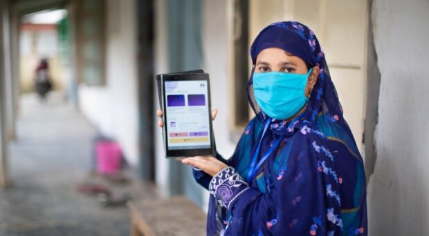 A community health worker showing a tablet with health information as she visits her local community