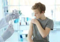 Hands of doctor preparing for vaccination and blurred patient on