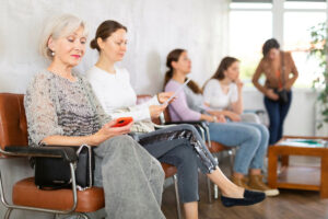 Senior woman using a smartphone sitting in a waiting room
