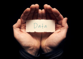 A man holding a card in cupped hands with a hand written message on it, Data.